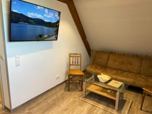 Gasthaus Kalte Herberge في Vöhrenbach: غرفة معيشة مع أريكة وتلفزيون على الحائط
