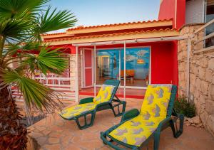 2 chaises assises sur une terrasse en face d'une maison dans l'établissement Villa Lagosta Stella Maris Exclusive, à Vila do Maio