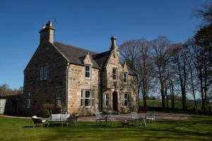 a large brick building with chairs and tables in front of it at Cardhu Country House in Aberlour