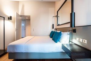 una camera da letto con un grande letto bianco con cuscini blu di Exclusive Top Floor 2BD by the TimeOut market a Lisbona