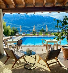 eine Terrasse mit einem Tisch, Stühlen und einem Pool in der Unterkunft Residence Dalco Suites & Apartments in Limone sul Garda