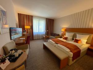 a hotel room with a large bed and a living room at Parkhotel Hohenfeld Münster in Münster