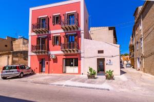 un edificio rosso con un'auto parcheggiata di fronte di MACRAME' SUITES a Sciacca