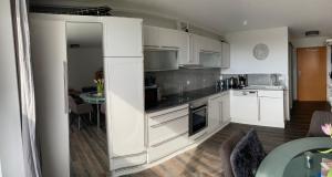 a kitchen with white cabinets and a dining room at Strandkorb in Ostseebad Sellin