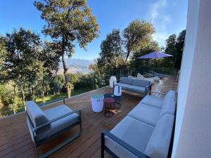 eine Terrasse mit Sofas, Tischen und einem Sonnenschirm in der Unterkunft Villa d'Architecte avec Piscine, vue imprenable. in Ajaccio