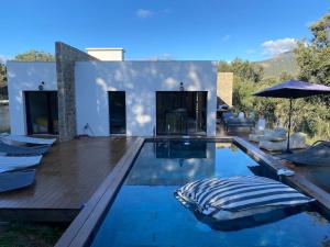 einen Pool mit Stühlen und einem Sonnenschirm in einem Haus in der Unterkunft Villa d'Architecte avec Piscine, vue imprenable. in Ajaccio