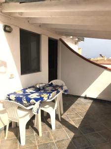 uma mesa e cadeiras numa varanda com uma televisão em Appartamenti L'Approdo del Gabbiano em Lampedusa