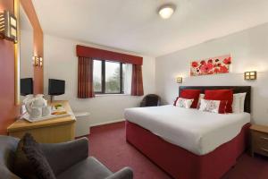 um quarto de hotel com uma cama grande e uma cadeira em Days Inn Hotel Gretna Green em Gretna Green