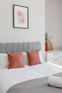 a white bedroom with a bed with orange pillows at Host Liverpool - Anfield Stadium Home, Cozy House for Family in Liverpool