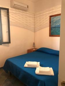 a bedroom with a blue bed with two towels on it at Appartamenti L'Approdo del Gabbiano in Lampedusa