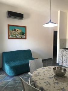 Appartamenti L'Approdo del Gabbiano في لامبيدوسا: غرفة معيشة مع أريكة زرقاء وطاولة