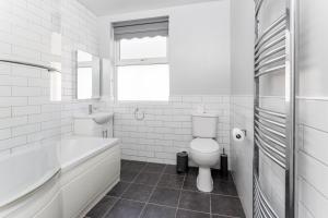 a white bathroom with a tub and a toilet at Host Liverpool - Anfield Stadium Home, Cozy House for Family in Liverpool