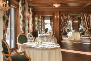 un comedor con mesas, sillas y ventanas en Tschuggen Grand Hotel - The Leading Hotels of the World en Arosa