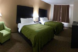 una habitación de hotel con 2 camas y una silla en Quality Inn & Suites en Paragould