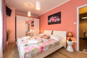 a bedroom with orange walls and a bed with pink sheets at Apartman Ruza in Krk