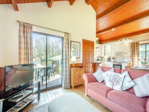 a living room with a pink couch and a tv at Bengairn in Fairgirth