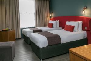 two beds in a hotel room with a red headboard at Hotel Balmoral in Newcastle upon Tyne
