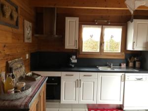 a kitchen with white cabinets and a sink and a window at Chalet avec Jacuzzi et Piscine, déco soignée esprit cocooning in Ramonchamp