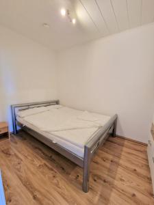 een bed in een witte kamer met een houten vloer bij Ferienpark O02-004 in Heiligenhafen