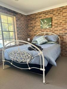 a bed in a bedroom with a brick wall at Stay on Lachlan in Cowra