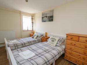 a bedroom with two beds and a dresser at Brynteg Cottage in Llanfyrnach