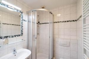 a white bathroom with a shower and a sink at Godewind ebenerdig in Westerland +16 photos