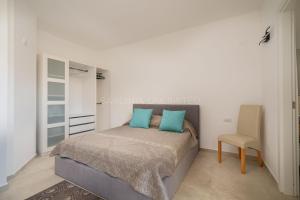 um quarto com uma cama com almofadas azuis e uma cadeira em Villetta Milla em Cannigione