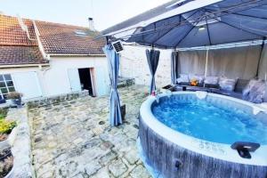 una bañera de hidromasaje en un patio trasero con sombrilla en Villa confortable avec Jacuzzi à Chevannes, en Chevannes