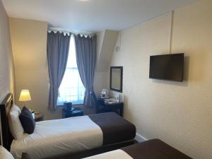 スカーバラにあるザ　グランド　スカボローのベッド2台、薄型テレビが備わるホテルルームです。