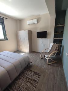 1 dormitorio con 1 cama, 1 silla y TV en Aithra 2 en Tripoli