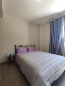 1 dormitorio con 1 cama blanca grande con almohadas moradas en Aithra 2 en Tripoli