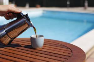 a person pouring coffee into a cup on a table at Casa Delbon Guest House in Aljezur