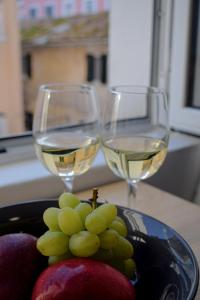 two glasses of white wine next to a plate of fruit at Studio Theotoki 2 in Corfu Town