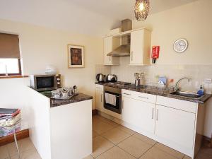 AnderbyにあるHarvest Cottageの白いキャビネット、シンク、電子レンジ付きのキッチンが備わります。
