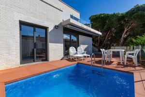 羅薩斯的住宿－RNET - Casa 4 - Vista Mar Almadrava Roses，房屋旁的游泳池配有椅子和桌子