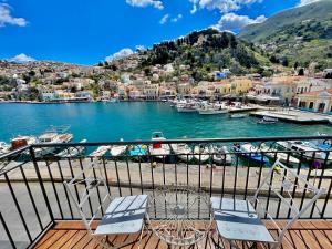 a balcony with two chairs and a marina with boats at Nikolakis, Seafront - Harbor view in Symi