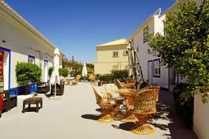 een patio met rieten stoelen, een tafel en een parasol bij Carvoeiro B&B and SPA in Carvoeiro