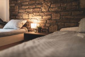 a bedroom with a stone wall with a bed and a lamp at ENIGMA in Vrdnik