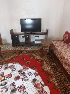 Villa kaoutar في مرتيل: غرفة معيشة مع تلفزيون بشاشة مسطحة وطاولة