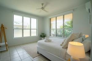 a white bedroom with a bed and a window at Nightcliff Retreat: Stylish 2BR Apt Near Foreshore in Nightcliff