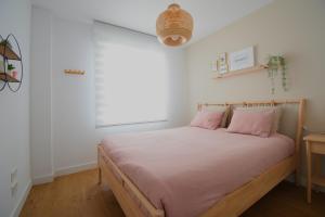 um quarto com uma cama com almofadas cor-de-rosa e uma janela em SEASIGHT APARTMENT CALACEITE em Torrox Costa