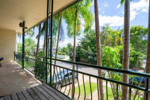 a balcony with palm trees and a car on a street at Nightcliff Retreat: Stylish 2BR Apt Near Foreshore in Nightcliff