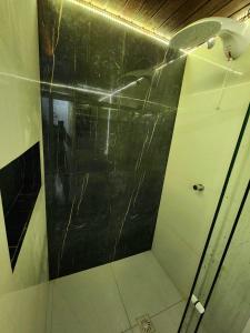 a bathroom with a shower with a black wall at Apartamento único na praia do Farol de Itapuã in Salvador