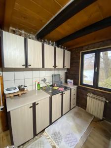 a kitchen with white cabinets and a sink in a room at Vikendica Lenka in Sijarinska Banja