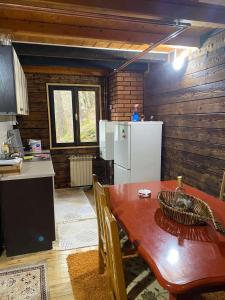 uma cozinha com uma mesa e um frigorífico branco em Vikendica Lenka em Sijarinska Banja