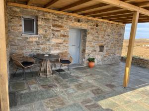 a patio with a table and chairs and a stone wall at Azul Houses Kythnos in Kithnos