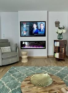 uma sala de estar com uma televisão de ecrã plano na parede em Appt Vue Mer Exceptionnelle Triple Expo - 70m 2ch - Rénové em Saint-Cast-le-Guildo