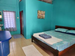1 dormitorio con 1 cama en una pared azul en Gecko Guesthouse, en Pantai Cenang