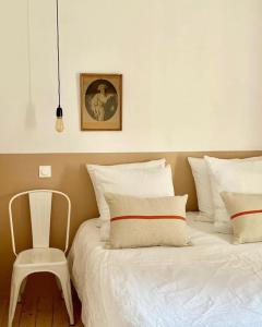 una camera con un letto bianco e una sedia di L’appartement 39 a Lons-le-Saunier
