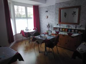 een woonkamer met 2 tafels en stoelen en een raam bij Merriedale Guest House in Paignton